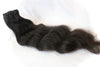 a bundle of black raw hair extensions in the wavy texture against a white surface