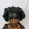 a photo of a black and gold hair bonnet with the emerald hair extensions logo in gold and green letters against a white background