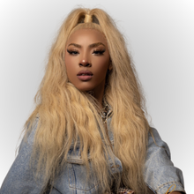  woman with blonde Indian wavy bundles, wearing a denim jacket and a top knot hairstyle.