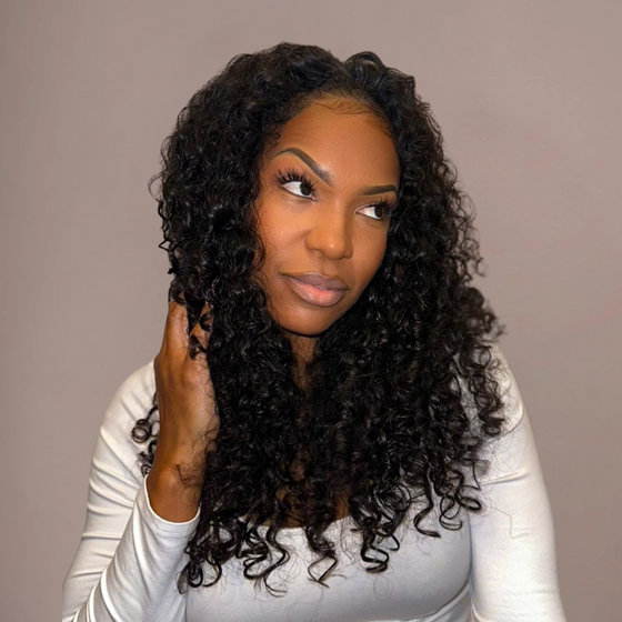 Woman with long, curly hair wearing a white top against a plain background