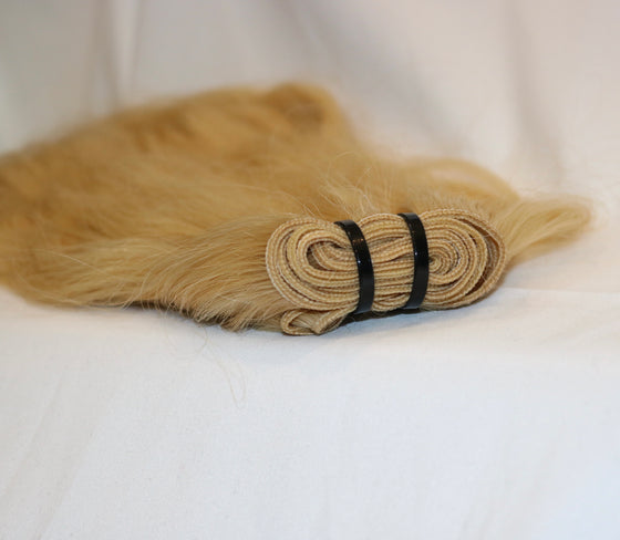 a bundle of blonde 613 wavy hair laid on a white surface