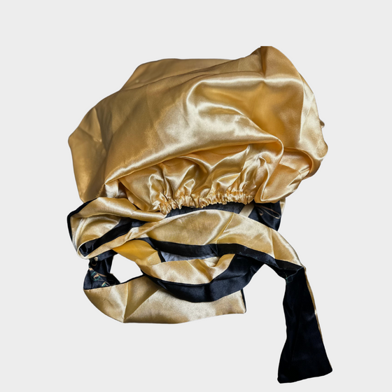 a photo of a black and gold hair bonnet with the emerald hair extensions logo in gold and green letters turned inside out against a white background