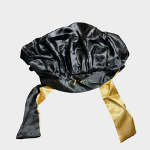  a photo of a black and gold hair bonnet with the emerald hair extensions logo in gold and green letters against a white background