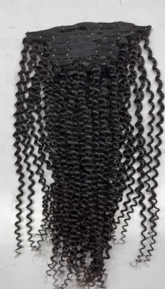 a set of clip in hair extensions in the kinky curly texture laid against a white surface