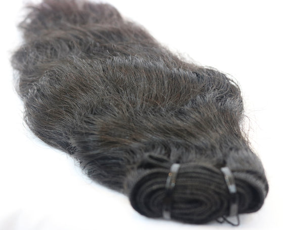 a bundle of black raw hair extensions in the wavy texture against a white surface