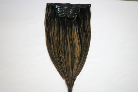 7 piece set of balayage colored hair clip in extensions laying on a white surface.