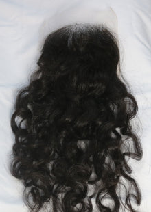  A closure in the texture natural curly laid out on a white surface.