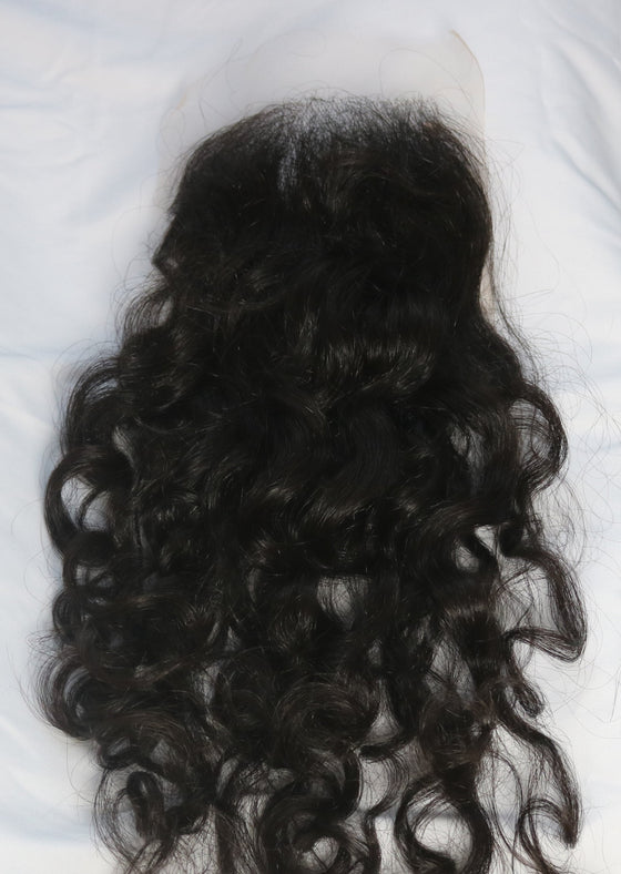 A closure in the texture natural curly laid out on a white surface.