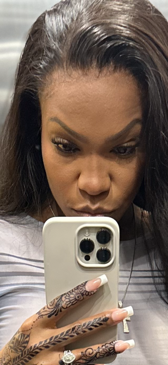 woman wearing undetectable thin hd lace, a grey top, holding a phone with a hand tattoo and french tip nails