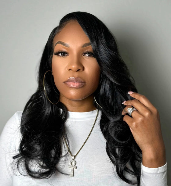 a woman in a white shirt wearing wavy clip in hair extensions styled with curls against a grey background