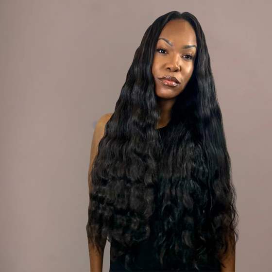 Woman with long, wavy black hair against a plain background