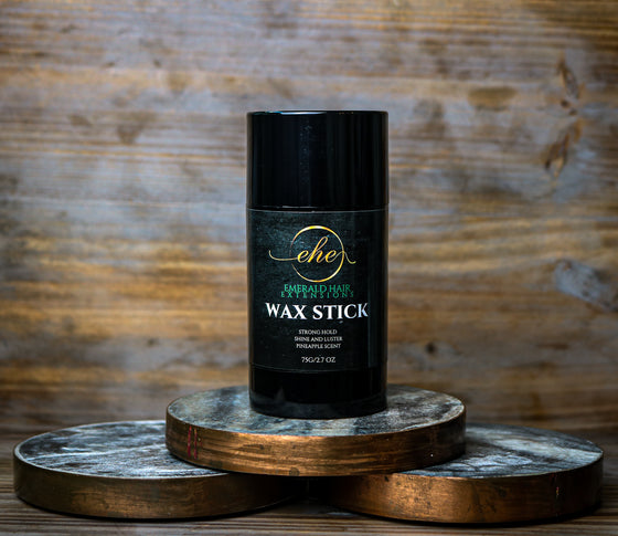 2.7 oz. wax stick with label that specifies strong hold, shine and luster, pineapple scented against a wood background.